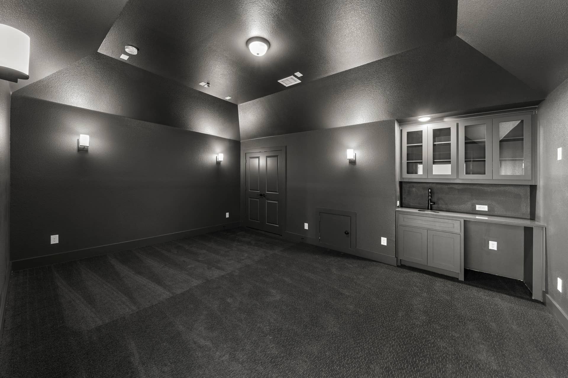 Monochromatic home theater room with dark walls and built-in cabinetry.