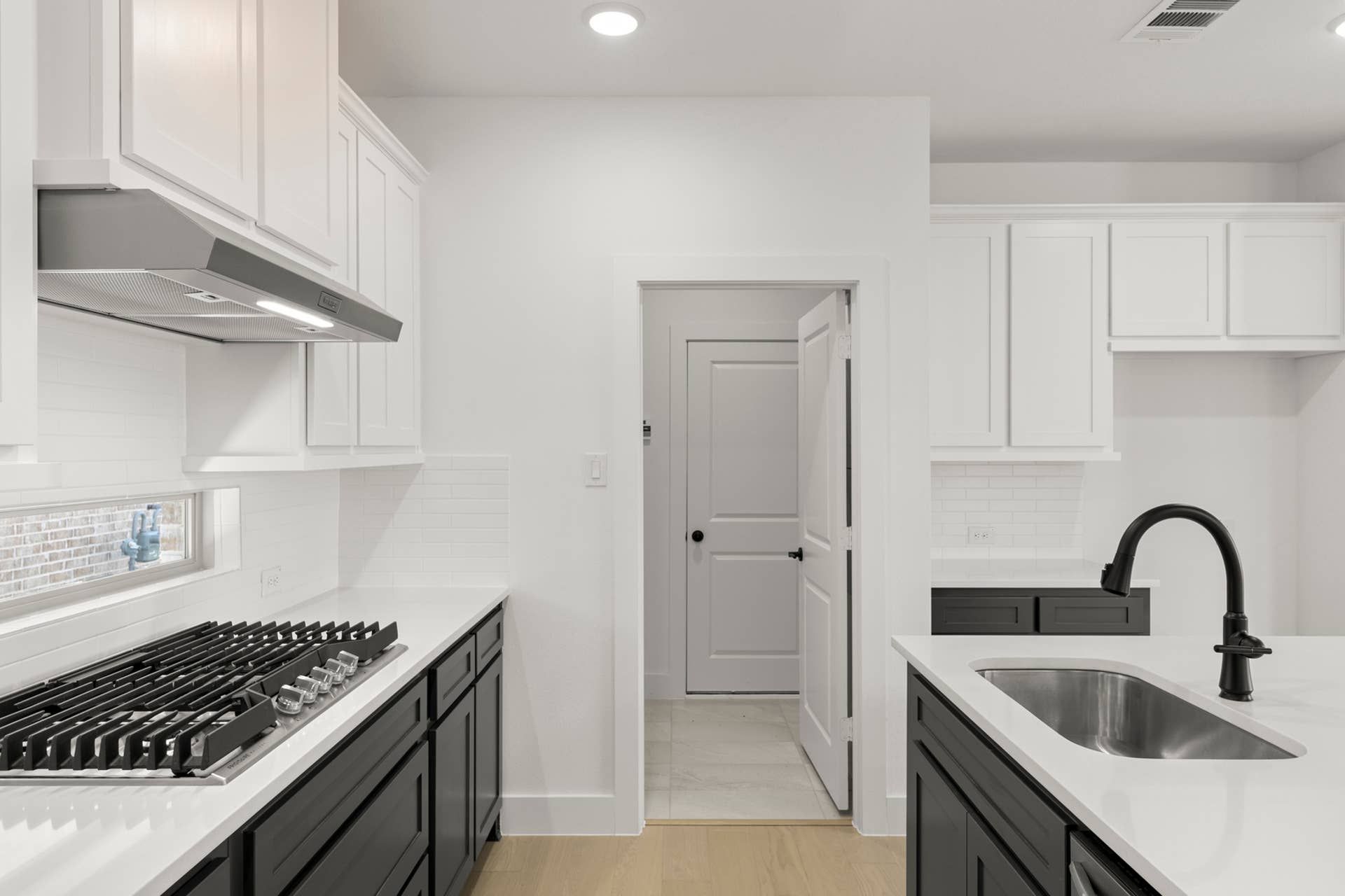 Modern kitchen with black cabinets, stainless steel sink, and built-in stovetop.
