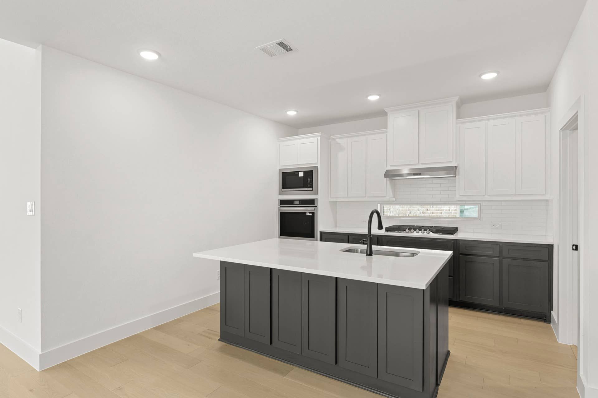 Modern kitchen with island, white cabinetry, and stainless steel appliances.