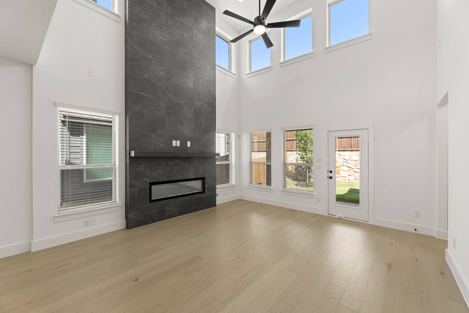Spacious living room with high ceiling, modern fireplace, and large windows.