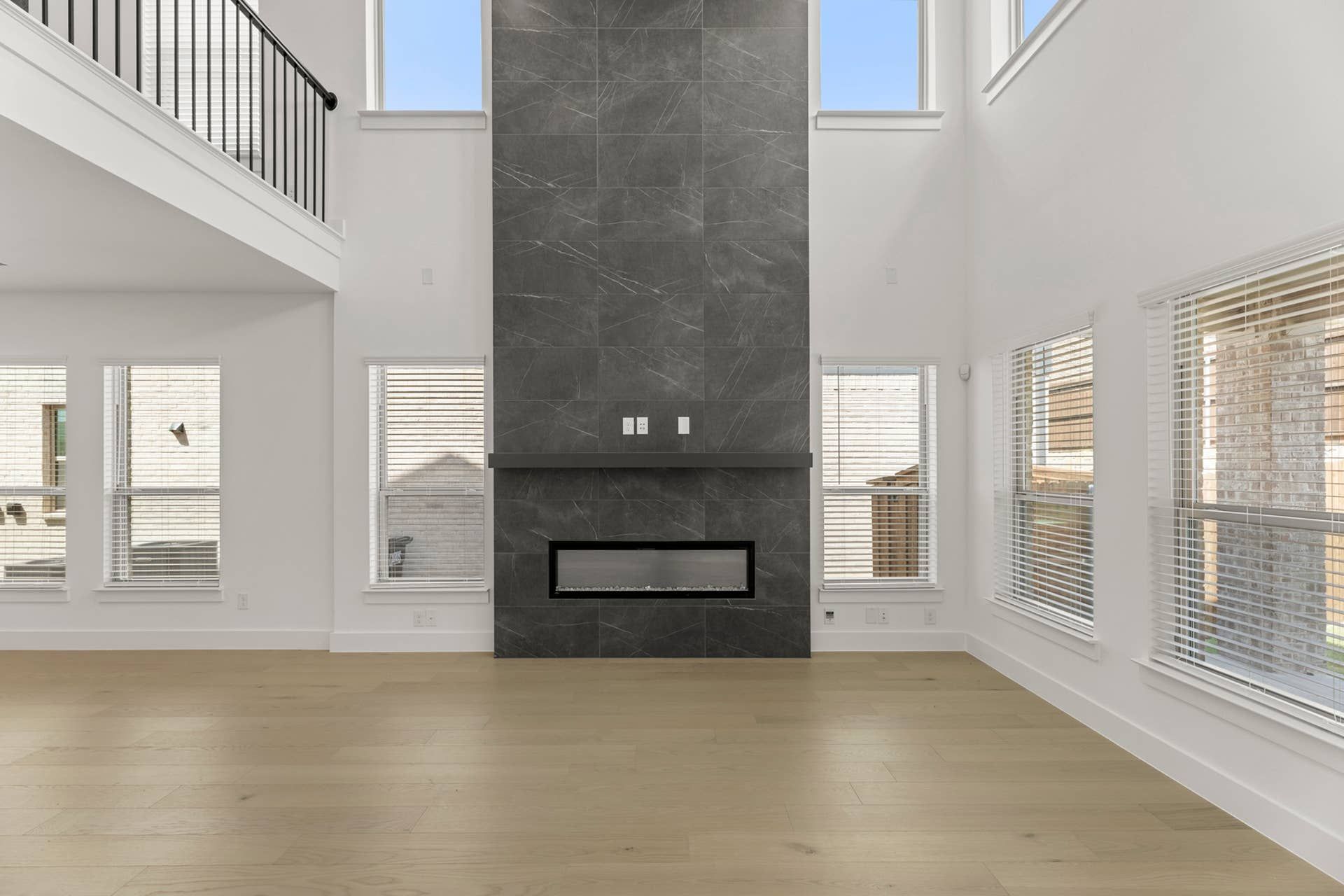 Spacious interior with tall grey stone fireplace and large windows.