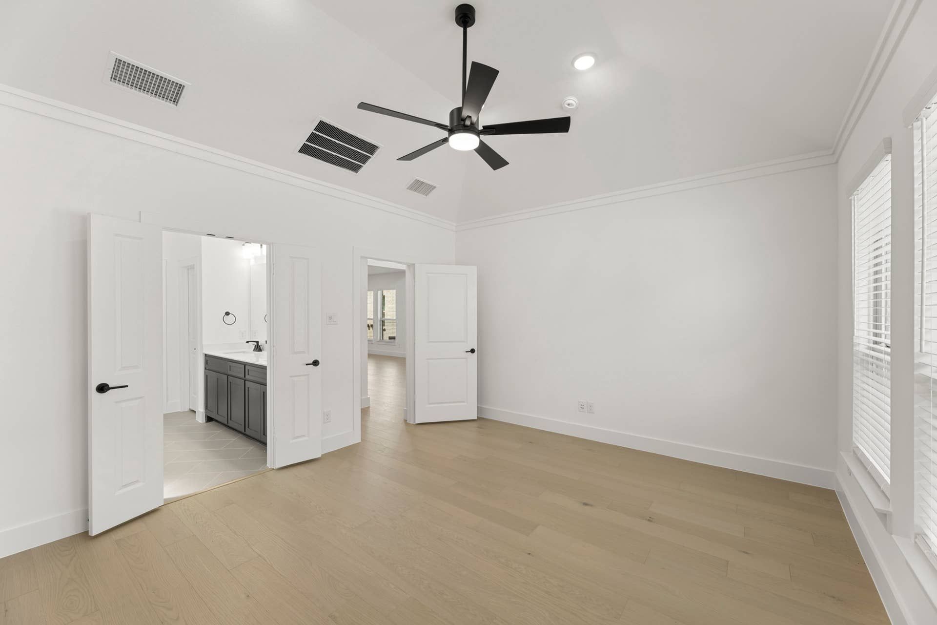 Spacious bedroom with vaulted ceiling, modern ceiling fan, and en suite bathroom access.