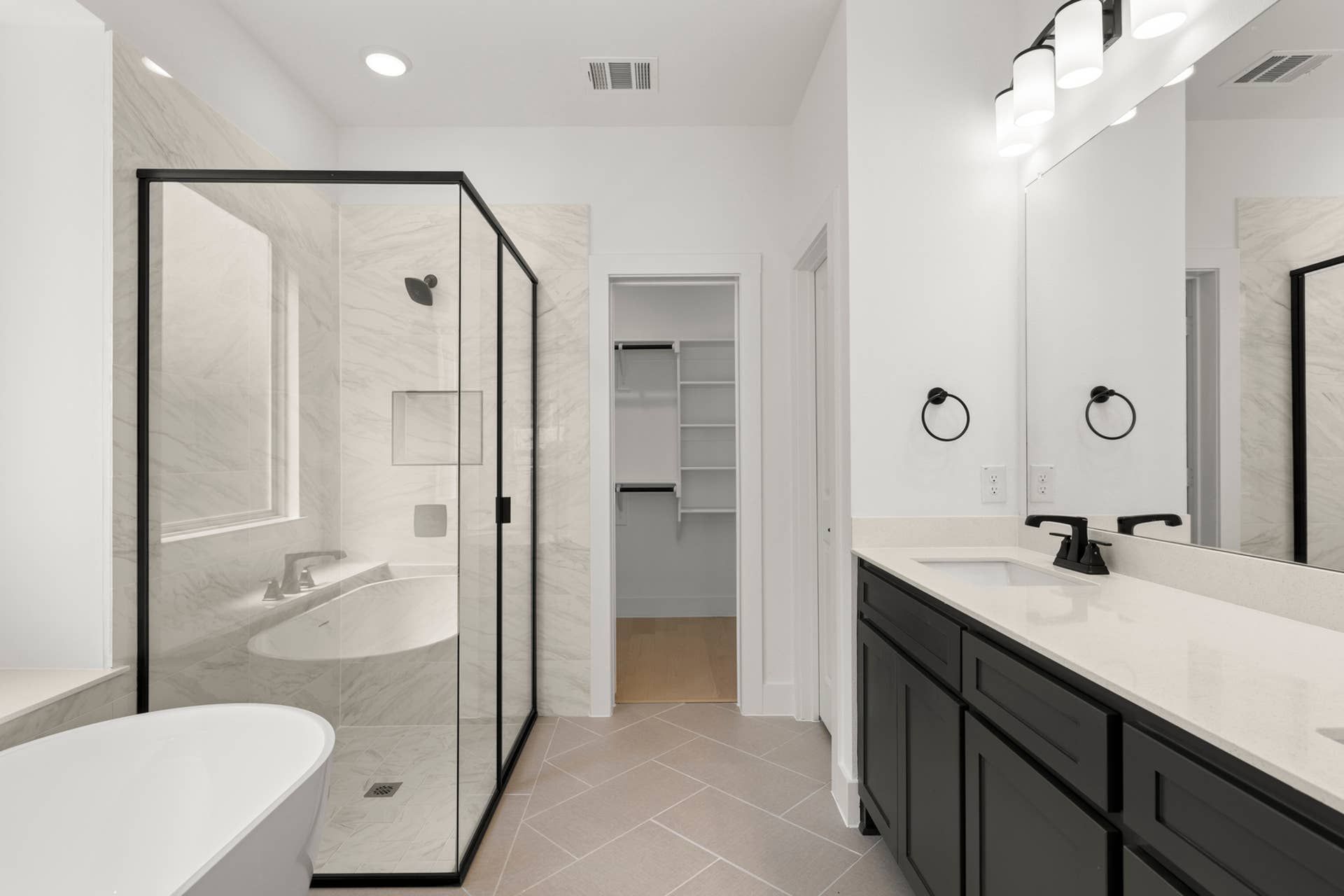 Modern bathroom with glass shower, freestanding tub, and dual-sink vanity.