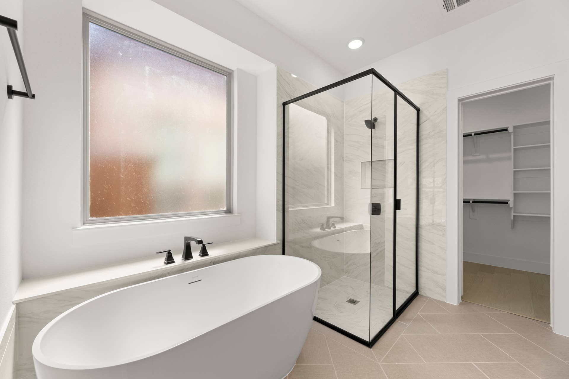 Modern bathroom with freestanding tub, glass shower, and frosted window.