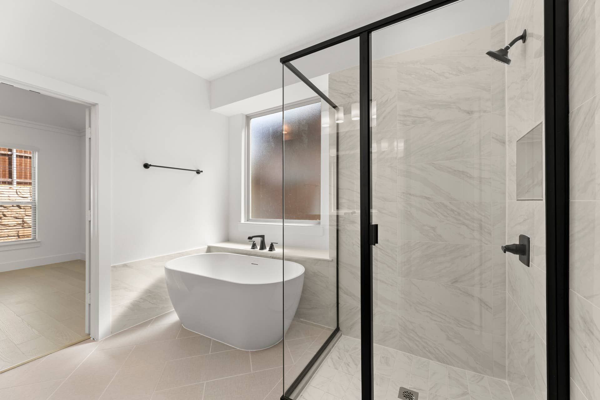 Modern bathroom with freestanding tub and glass-enclosed shower.