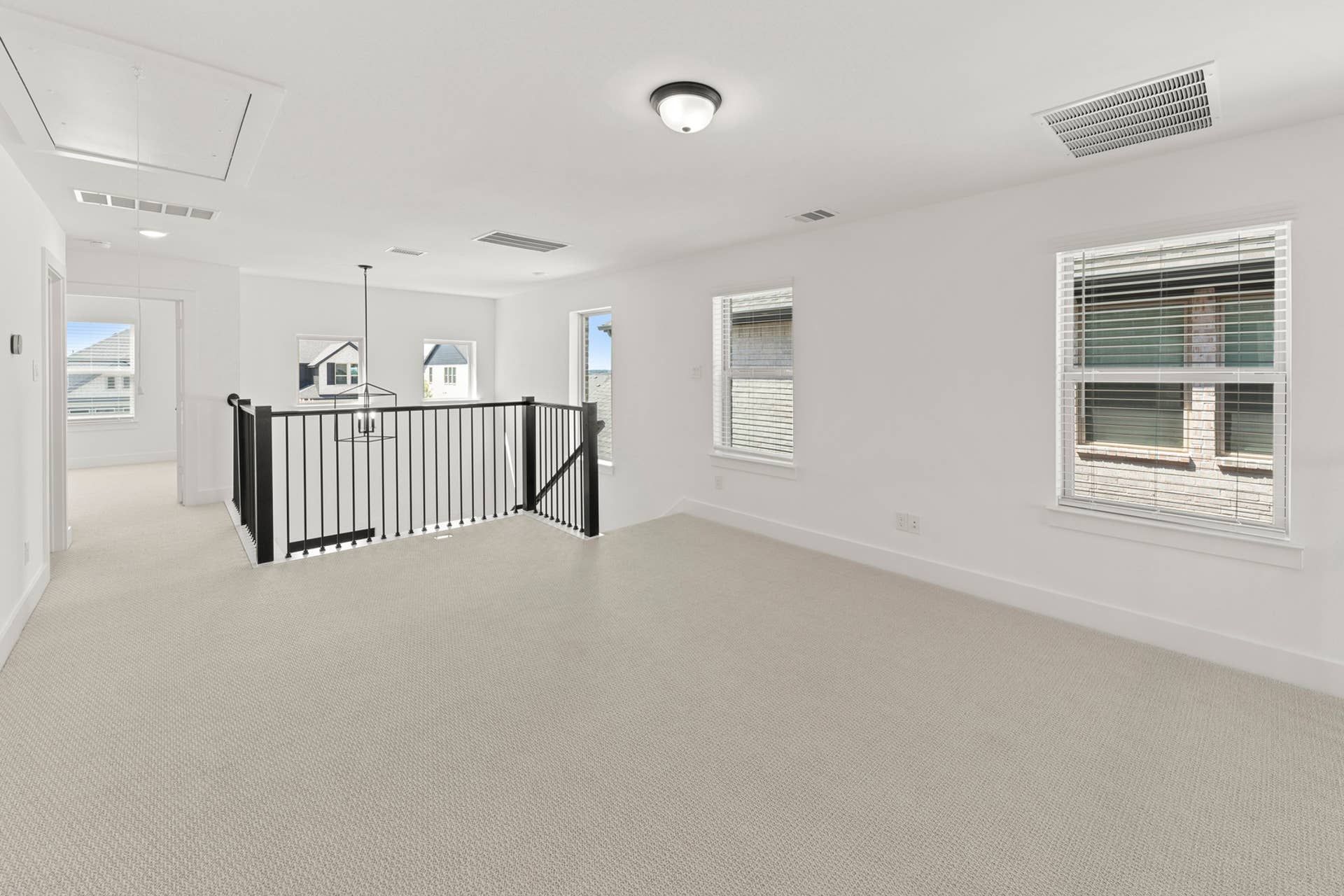 Bright loft area with carpet flooring and modern railing.