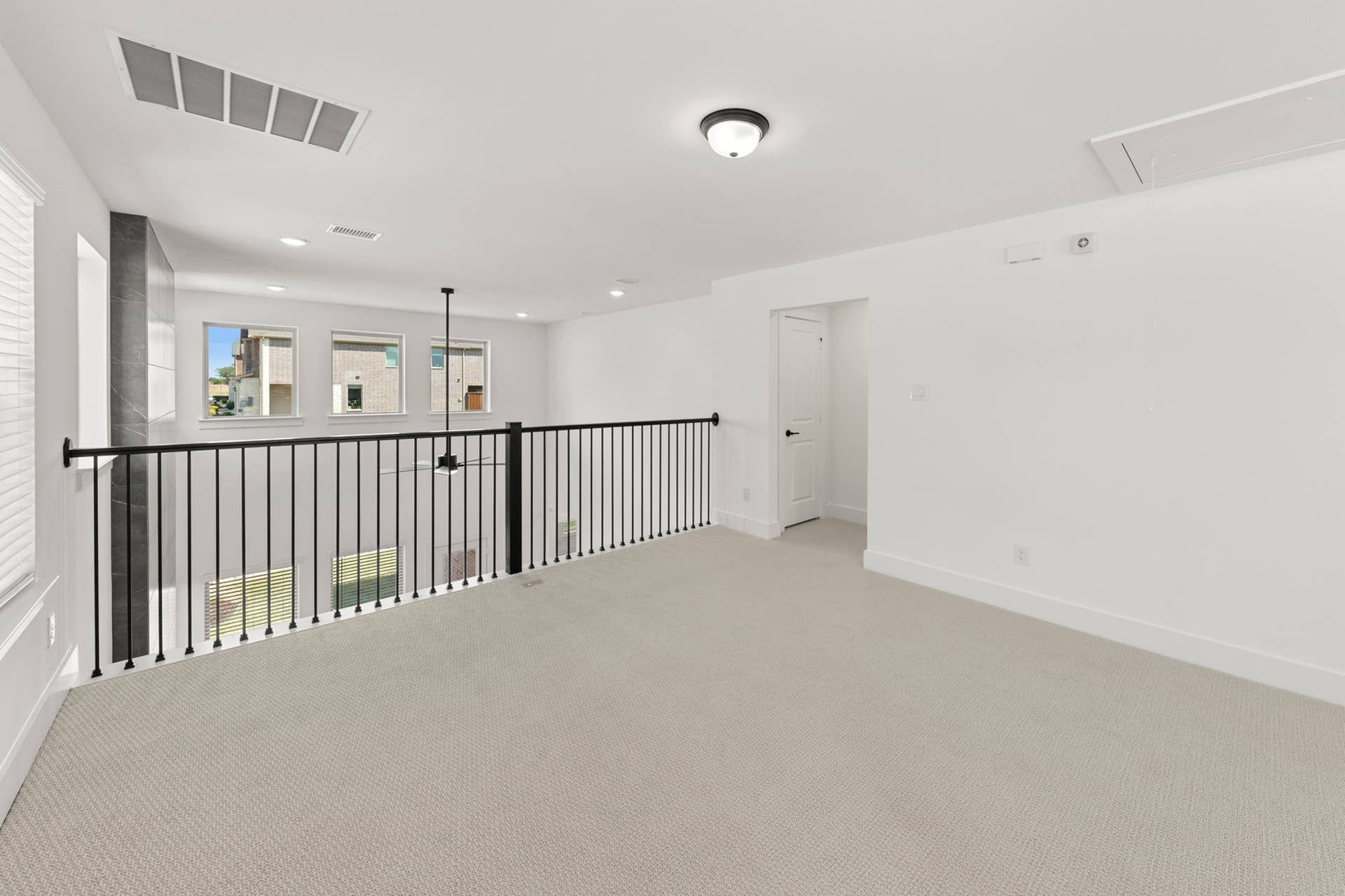Bright open loft with railing and large windows overlooking outdoor view.