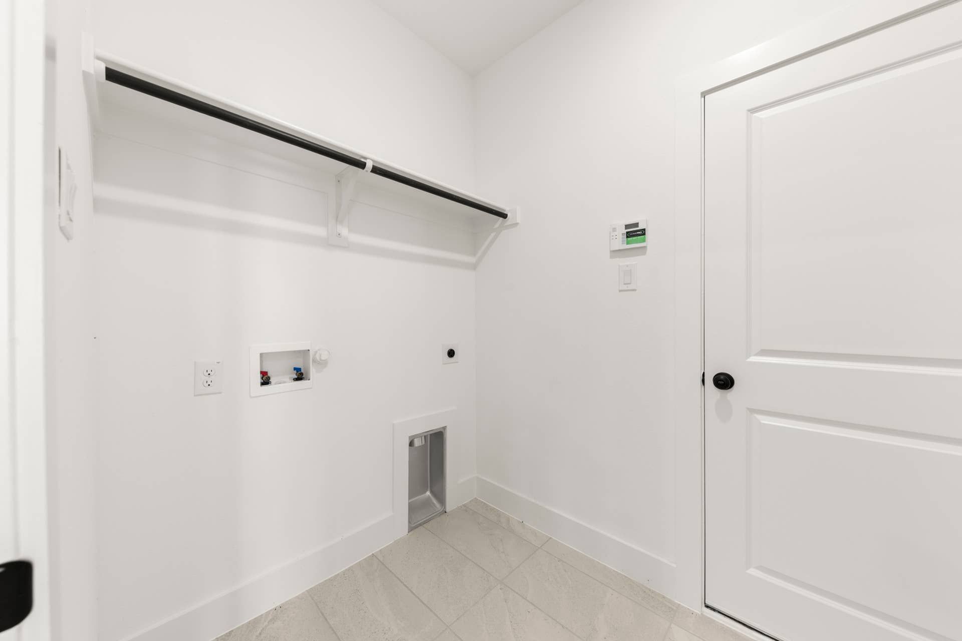 Utility room with washer connections and shelving in a modern home interior.