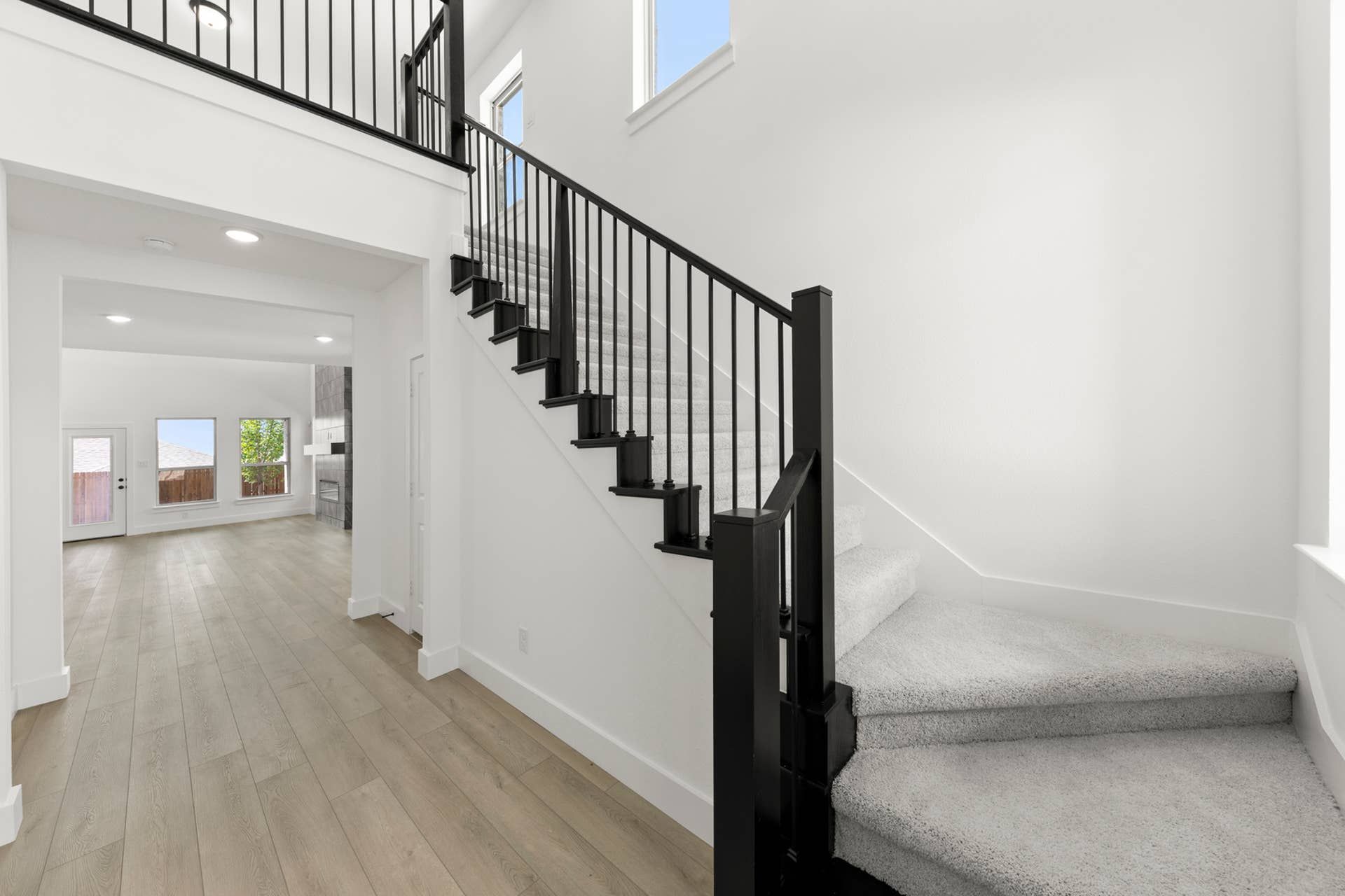Modern entryway with carpeted stairs and open living area, natural light flooding in.