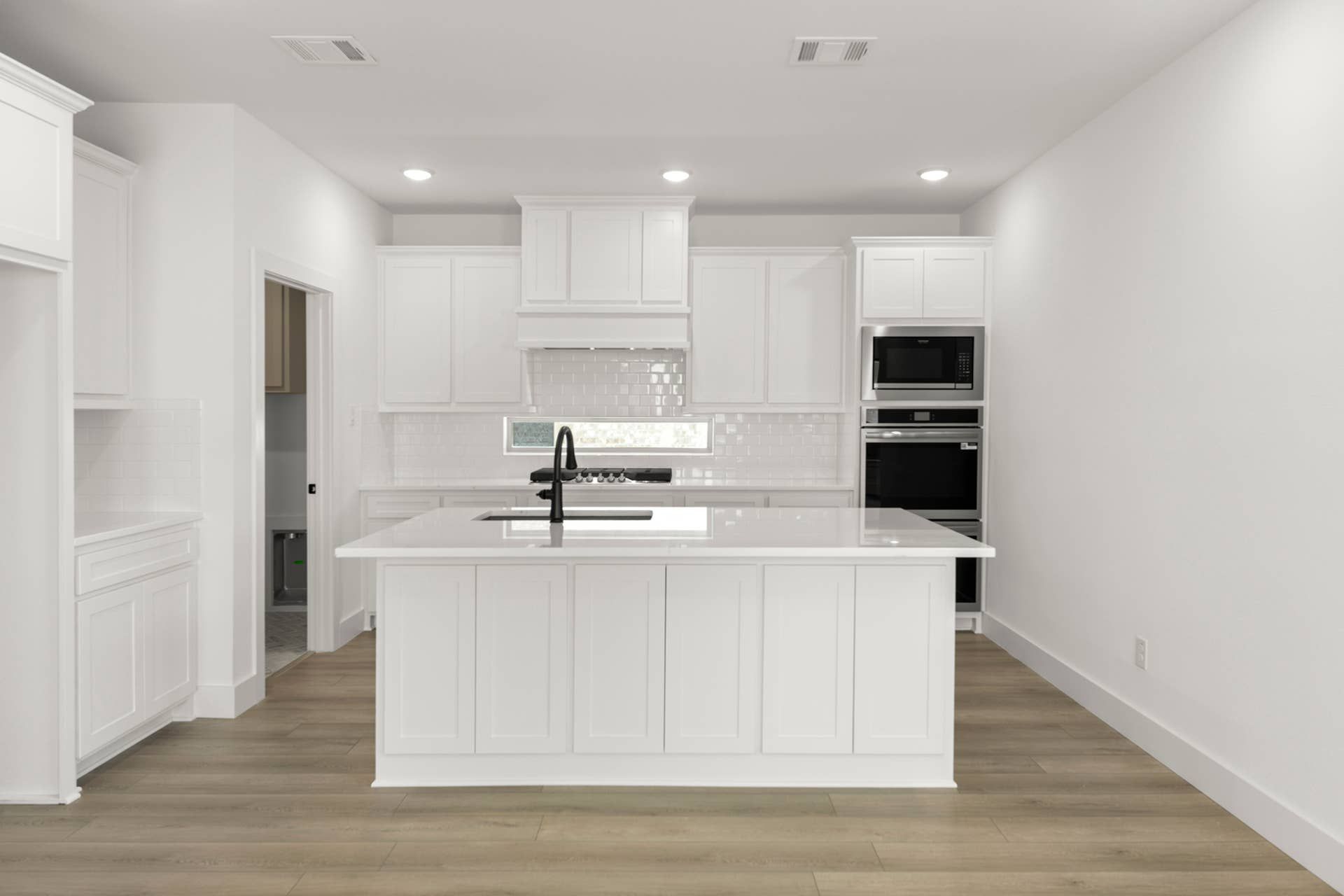 Modern kitchen with white cabinetry, island, and stainless steel appliances.