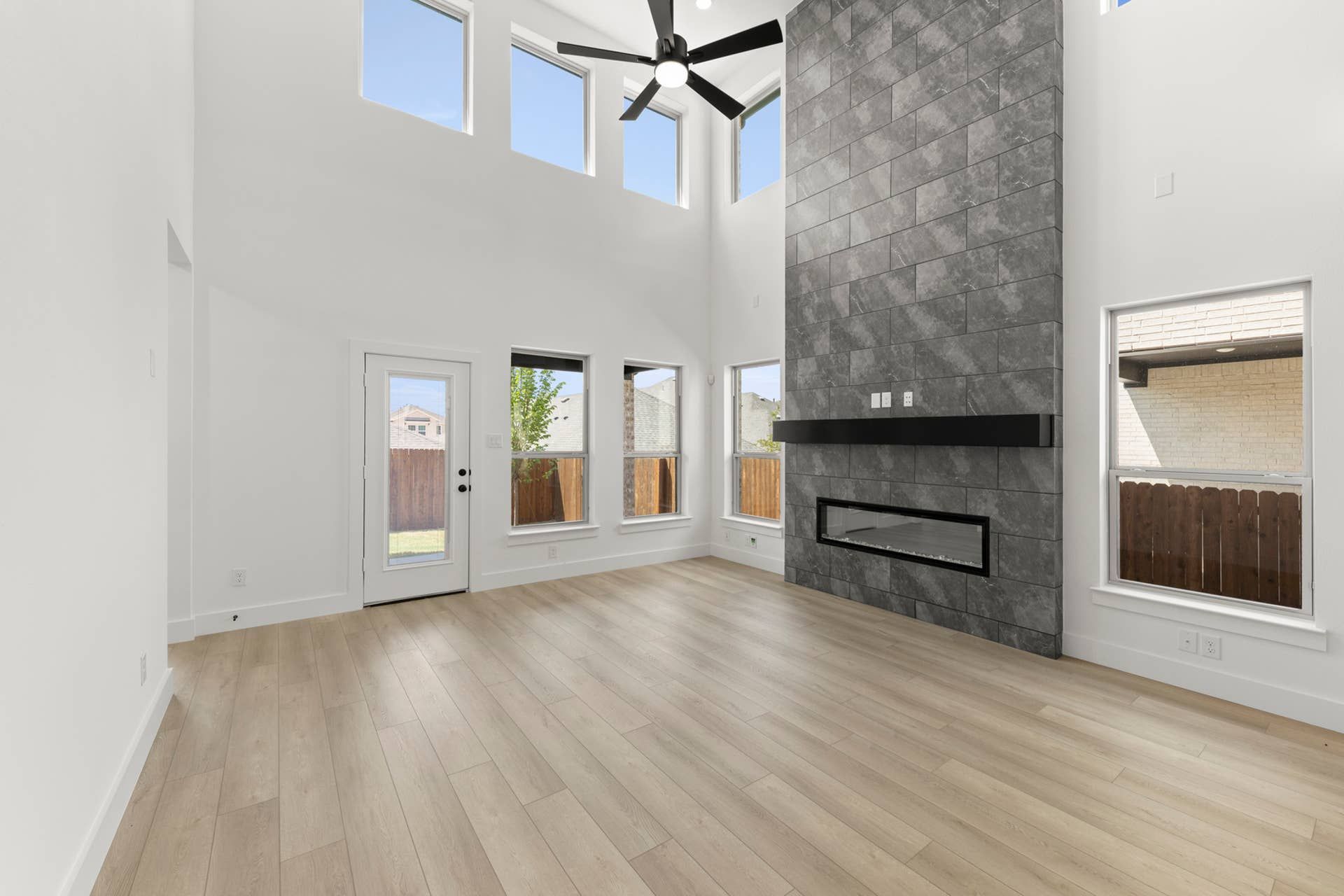 Spacious modern living room with high ceilings and large stone fireplace feature.