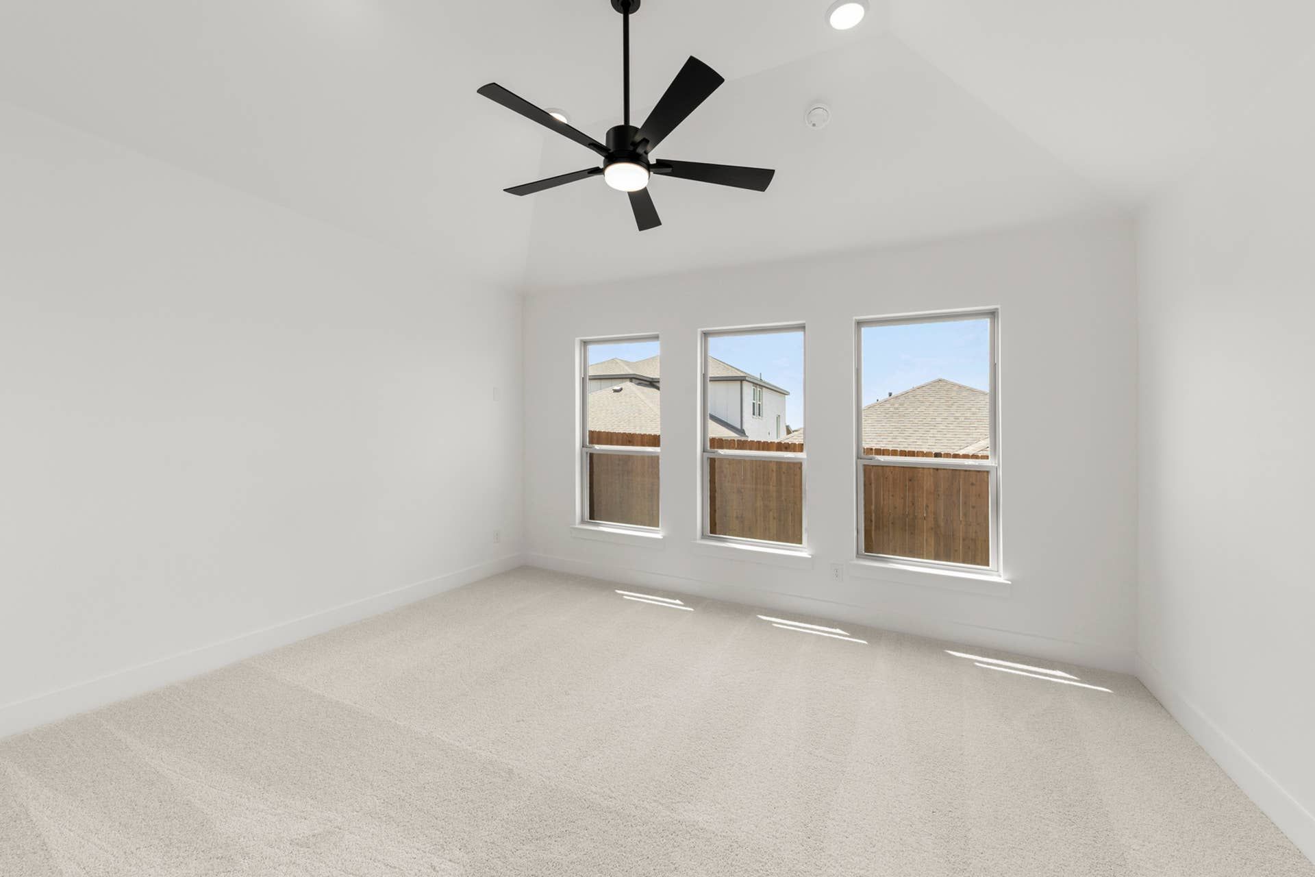 Spacious bedroom with ceiling fan and three large windows.