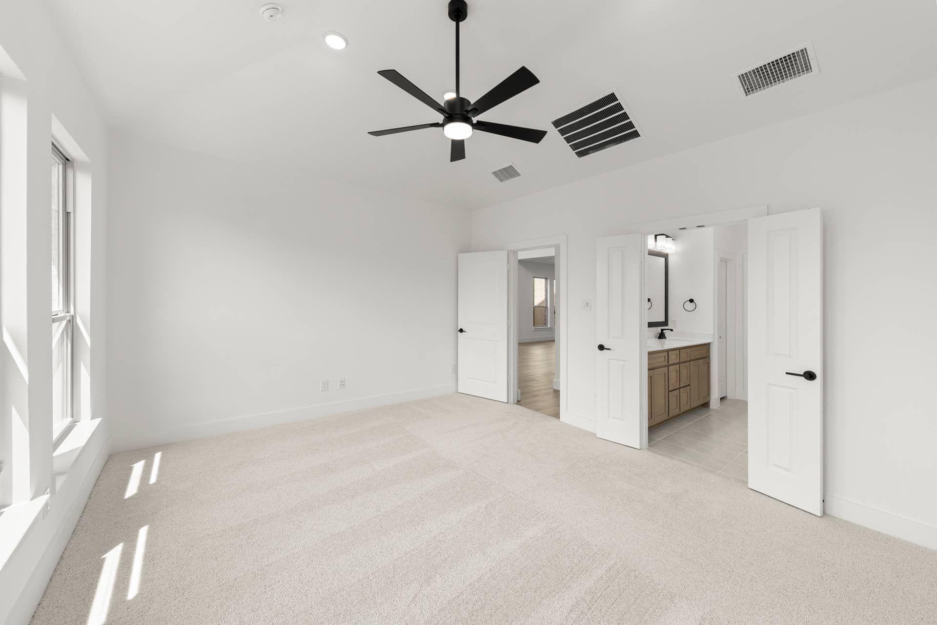 Spacious primary bedroom with ceiling fan and en-suite bathroom.
