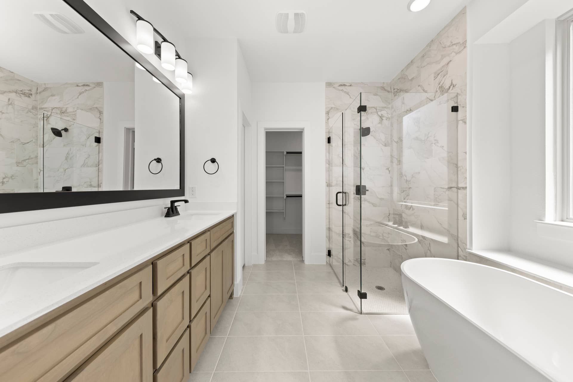Luxurious bathroom with freestanding tub, glass shower, and double vanity.