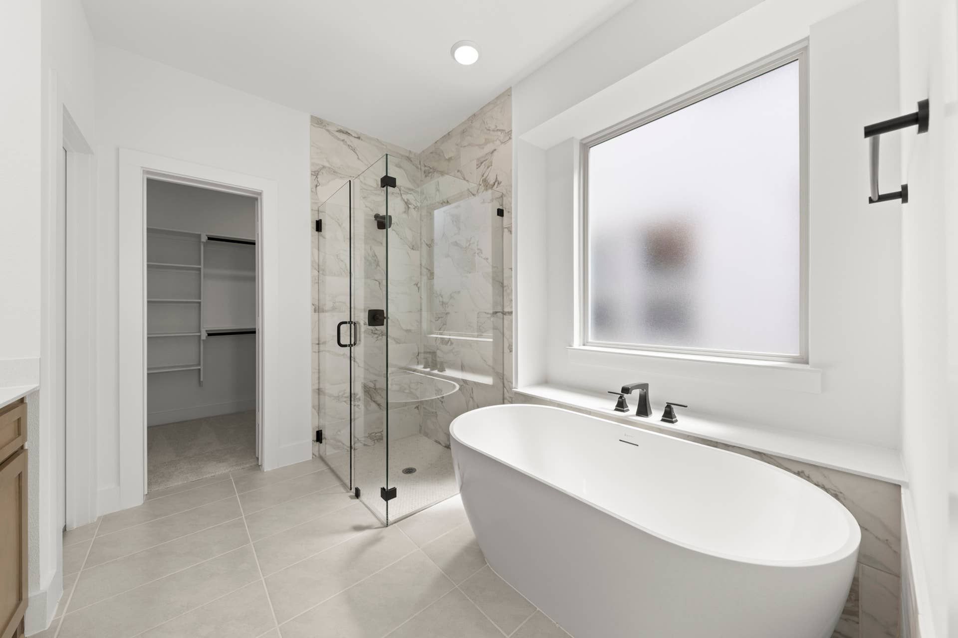Modern bathroom with freestanding tub, glass shower, and walk-in closet.