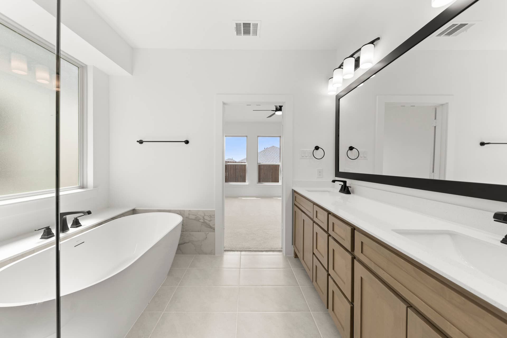 Modern bathroom with freestanding tub, double vanity, and large mirror.