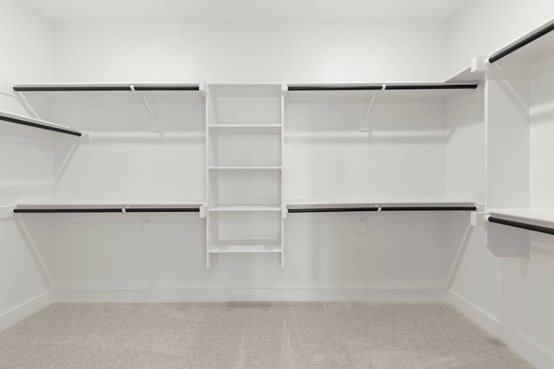 Spacious walk-in closet with white shelving and hanging rods.