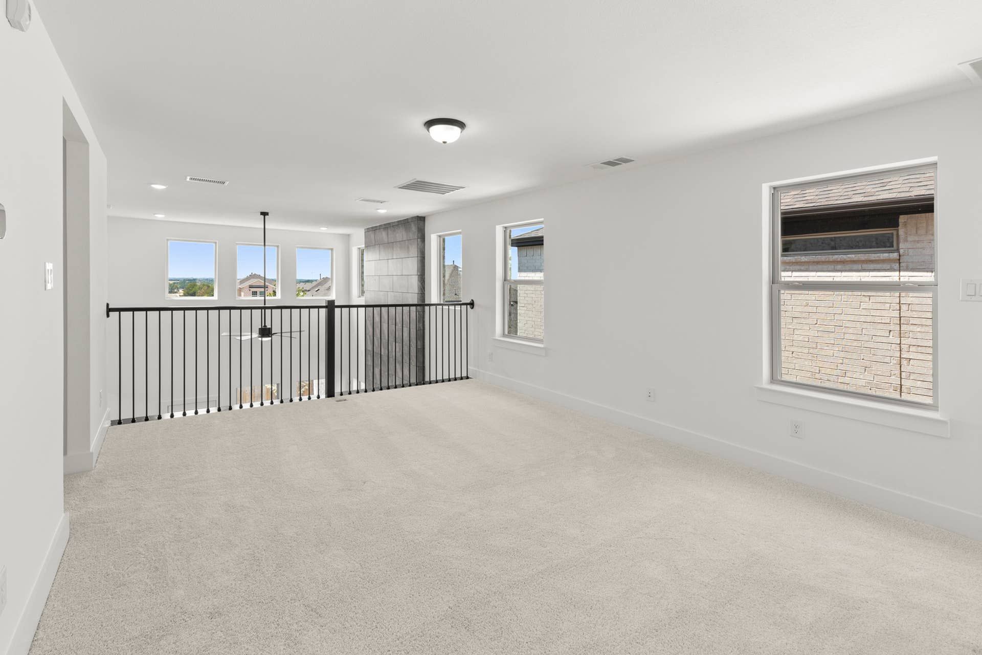 Spacious upper-level loft with carpet and railing overlooking lower floor.