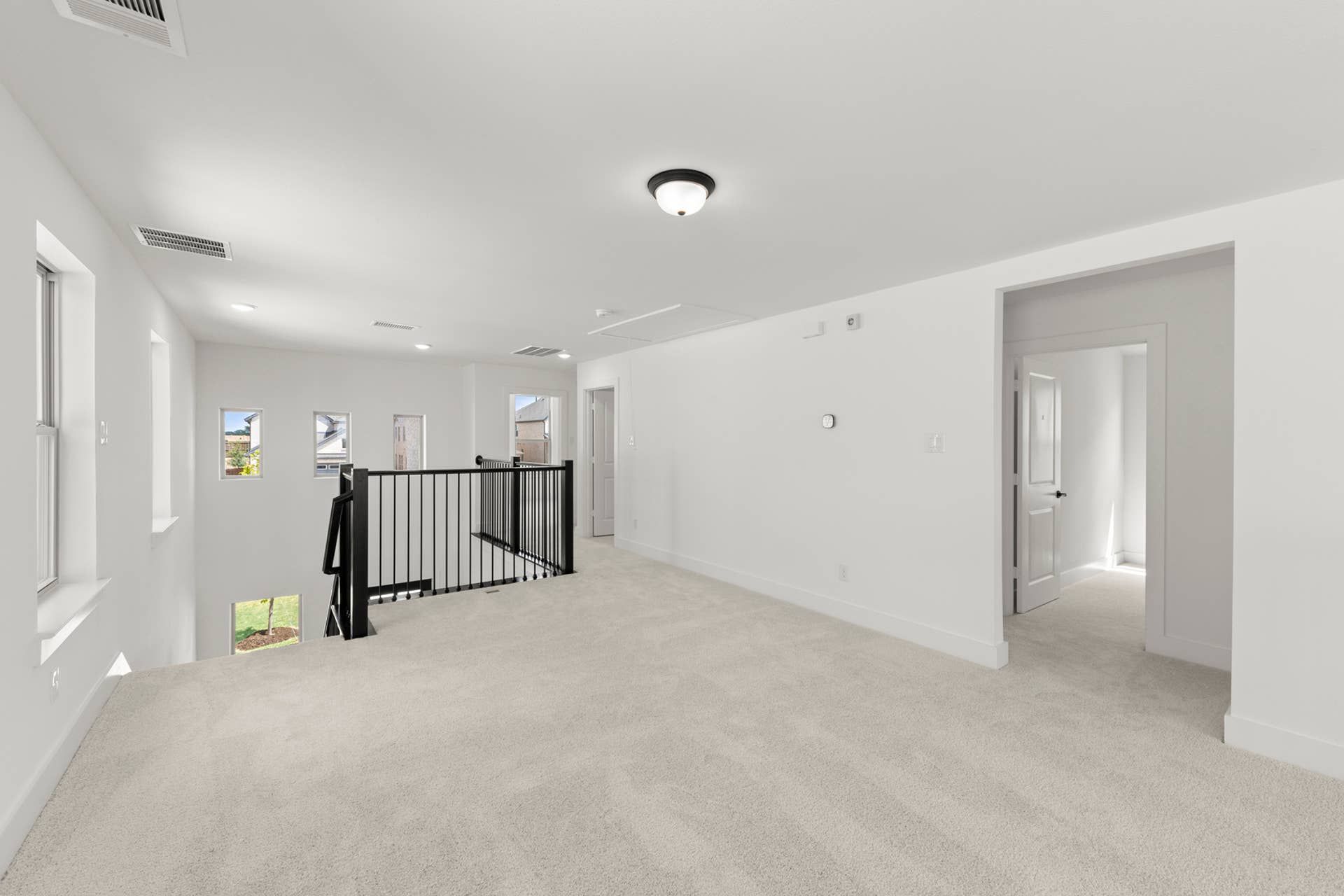 Spacious interior with carpeted flooring and modern railing.