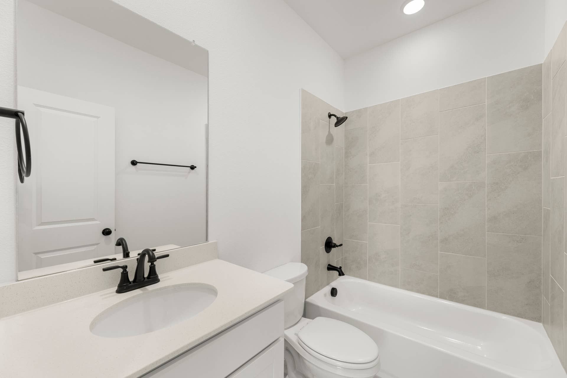 Modern bathroom with tiled shower, sleek fixtures, and vanity mirror.