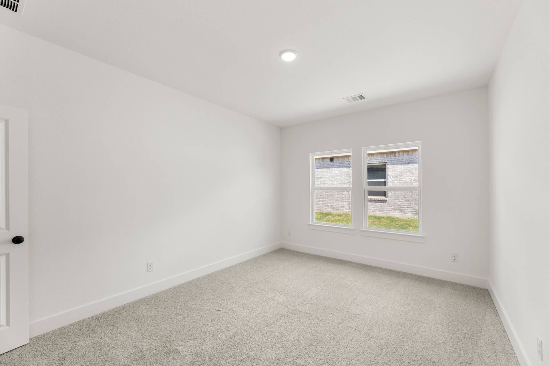 Bright study room with carpet and two large windows.