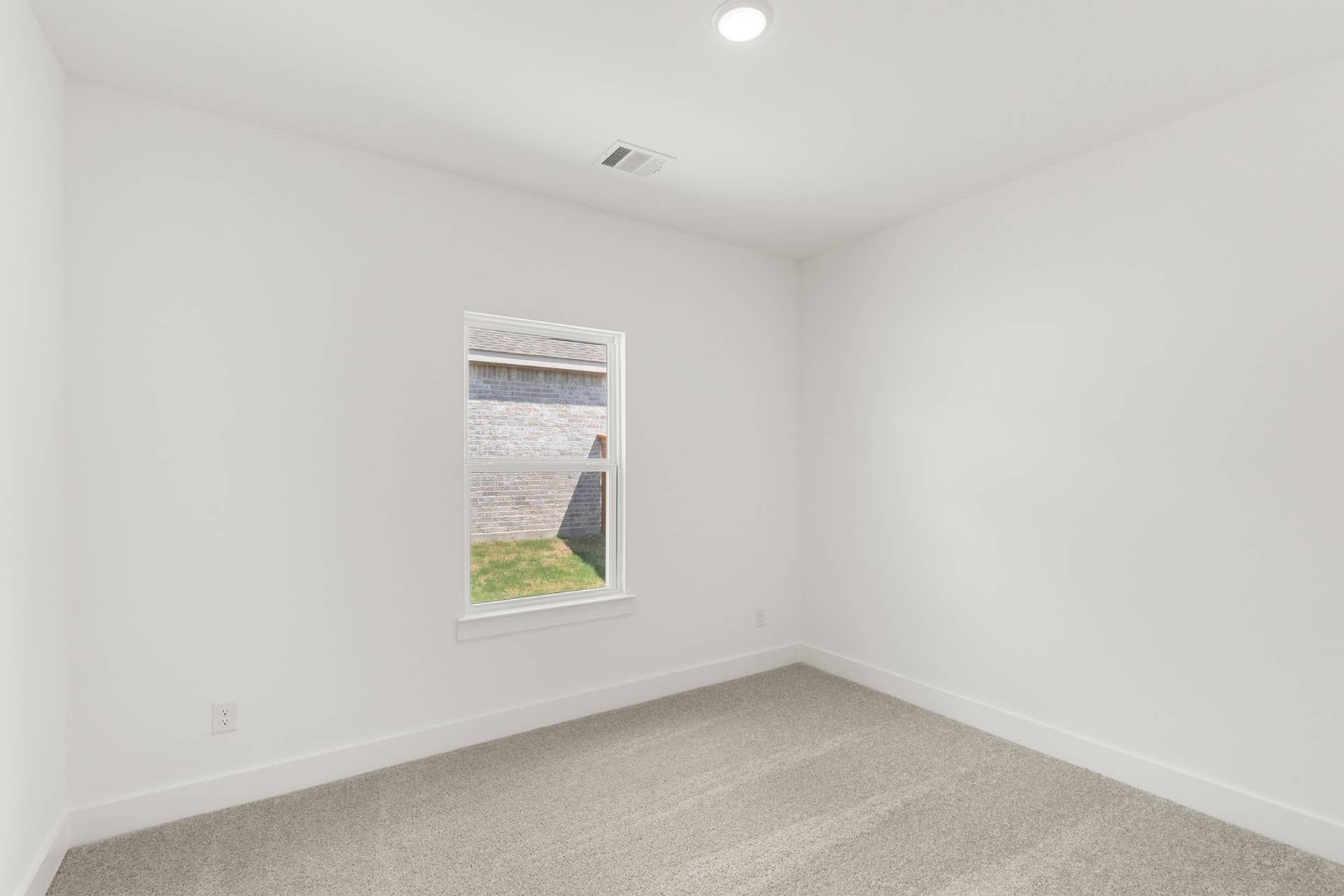 Bright empty bedroom with white walls and carpeted floor.