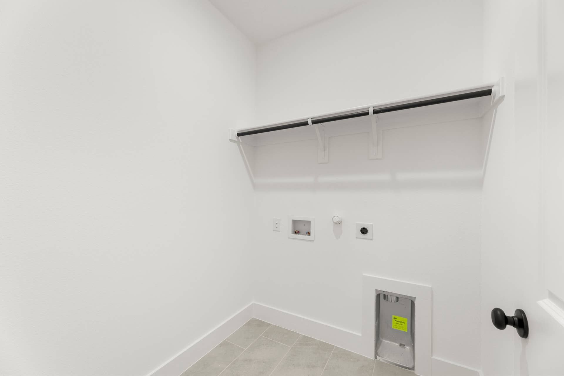 Utility room with washer and dryer hookups and shelf.