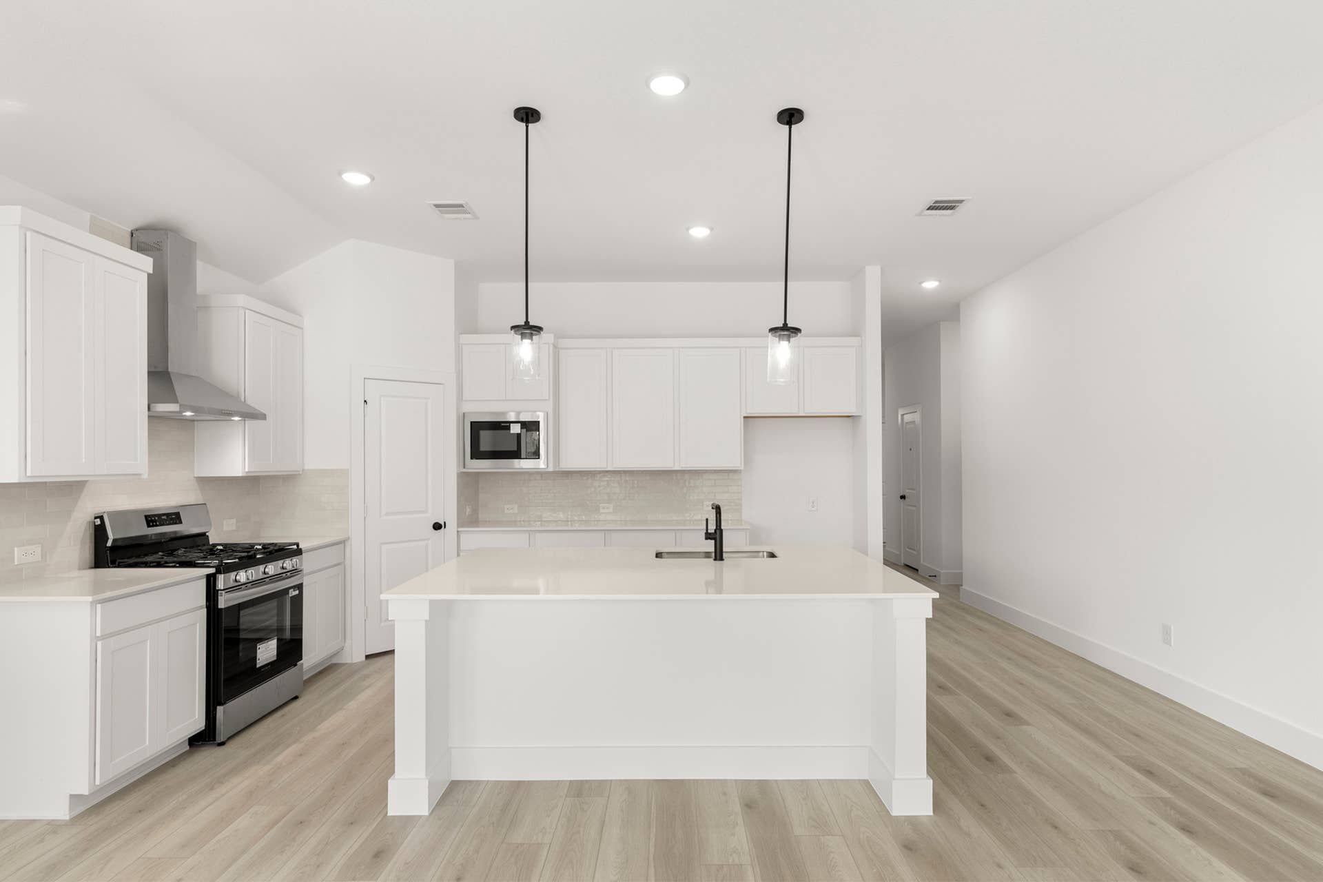 Modern kitchen with white cabinetry, island, and pendant lighting.