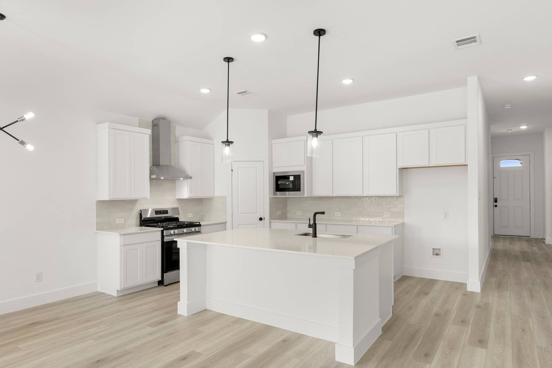 Modern kitchen with white cabinets, island, and stainless steel appliances.