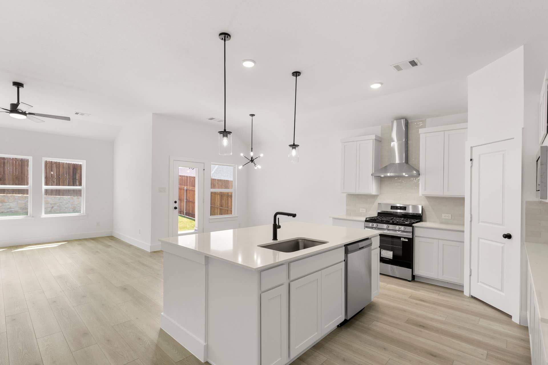 Modern kitchen with island, pendant lighting, and stainless steel appliances.
