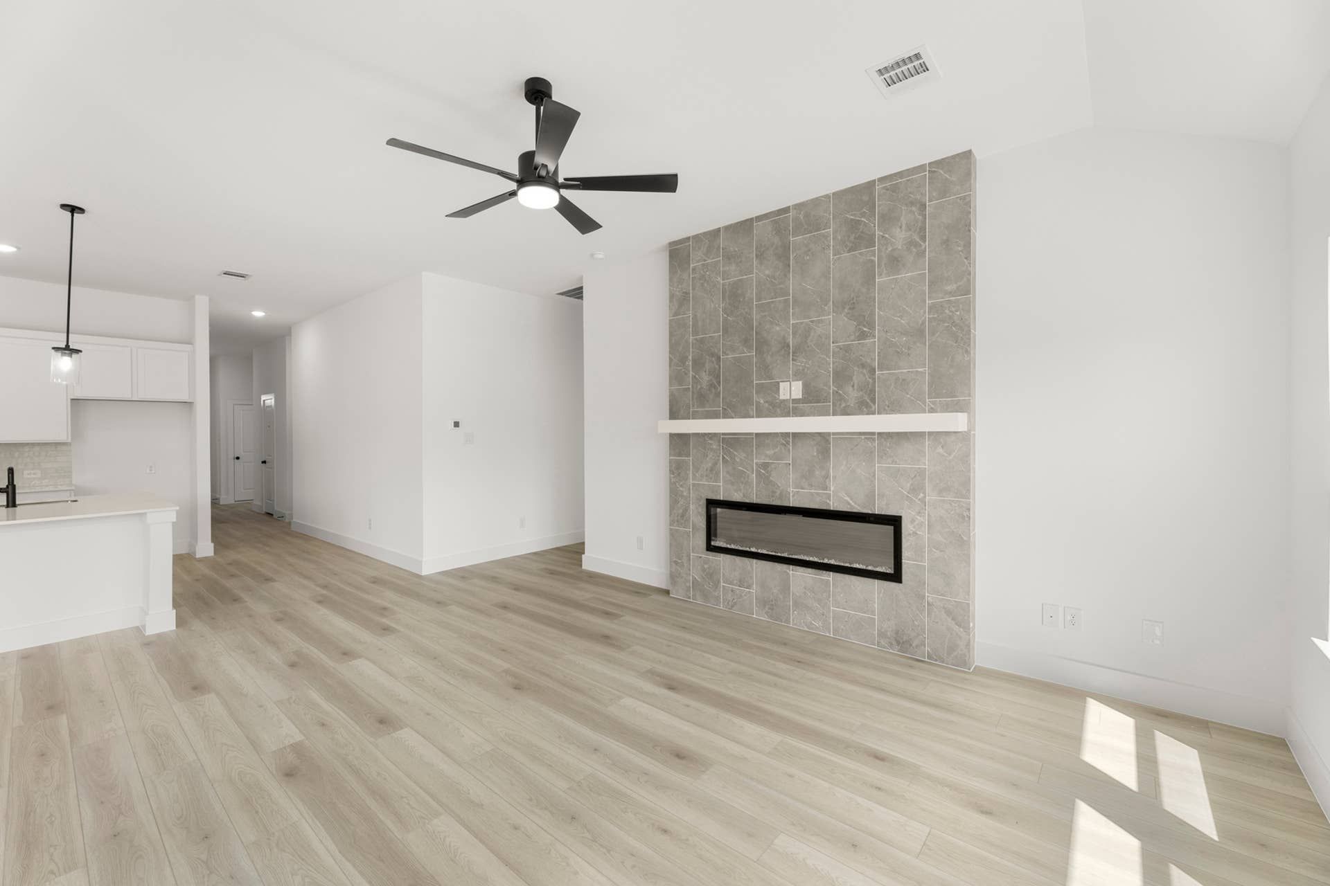 Modern living room with tiled fireplace and ceiling fan.