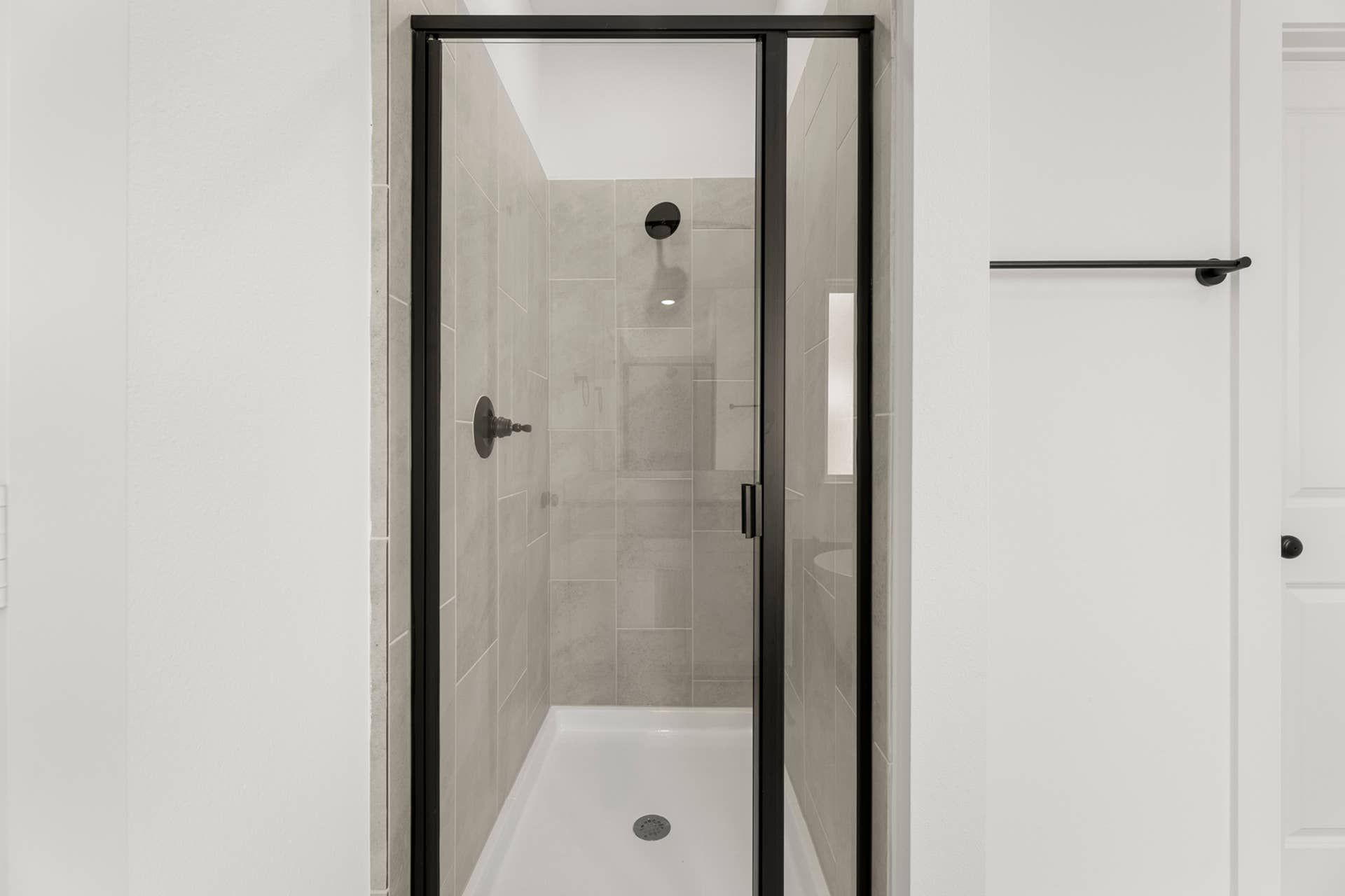 Modern bathroom with glass-enclosed shower and black fixtures.
