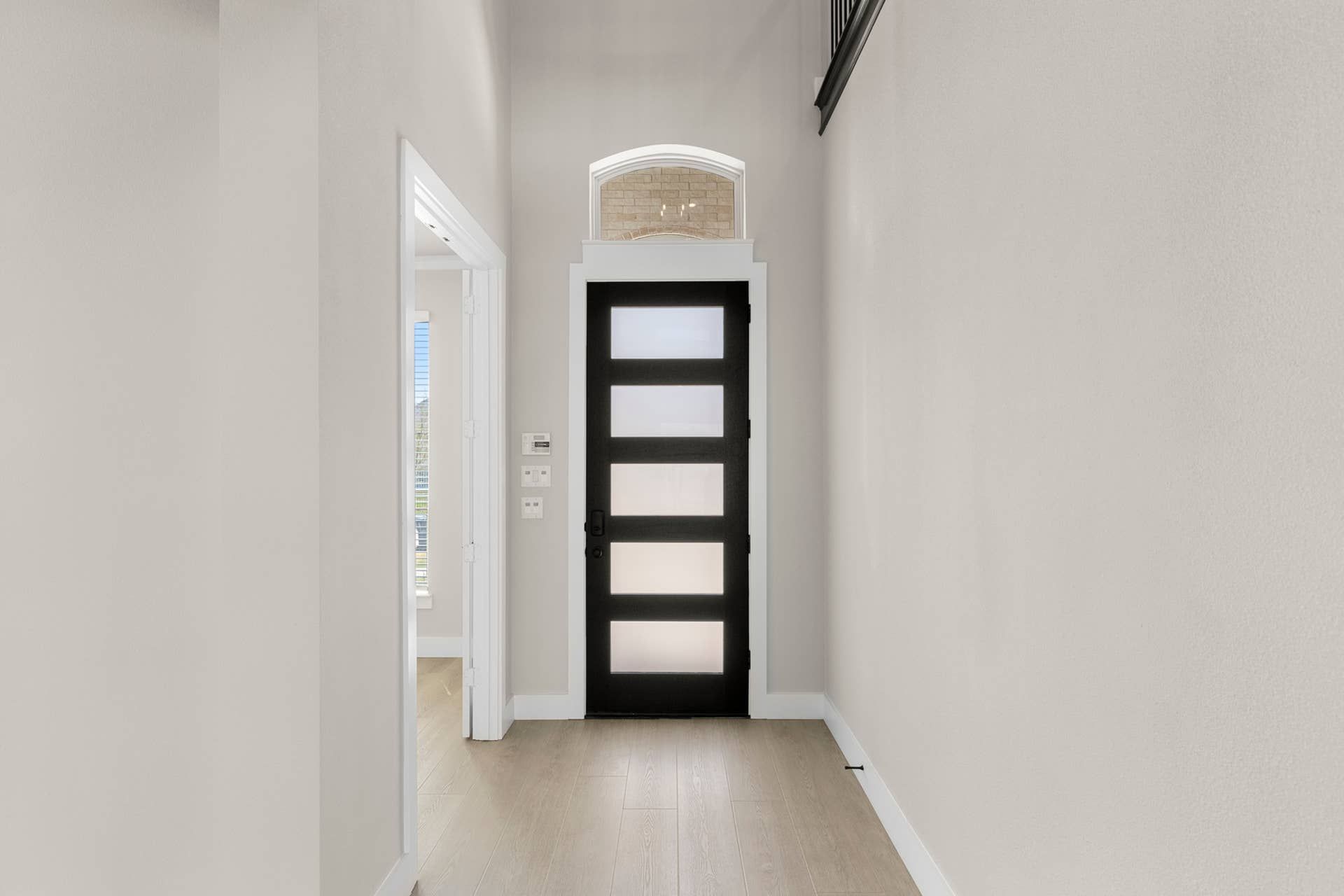 Modern entryway with frosted glass door and light wood flooring.