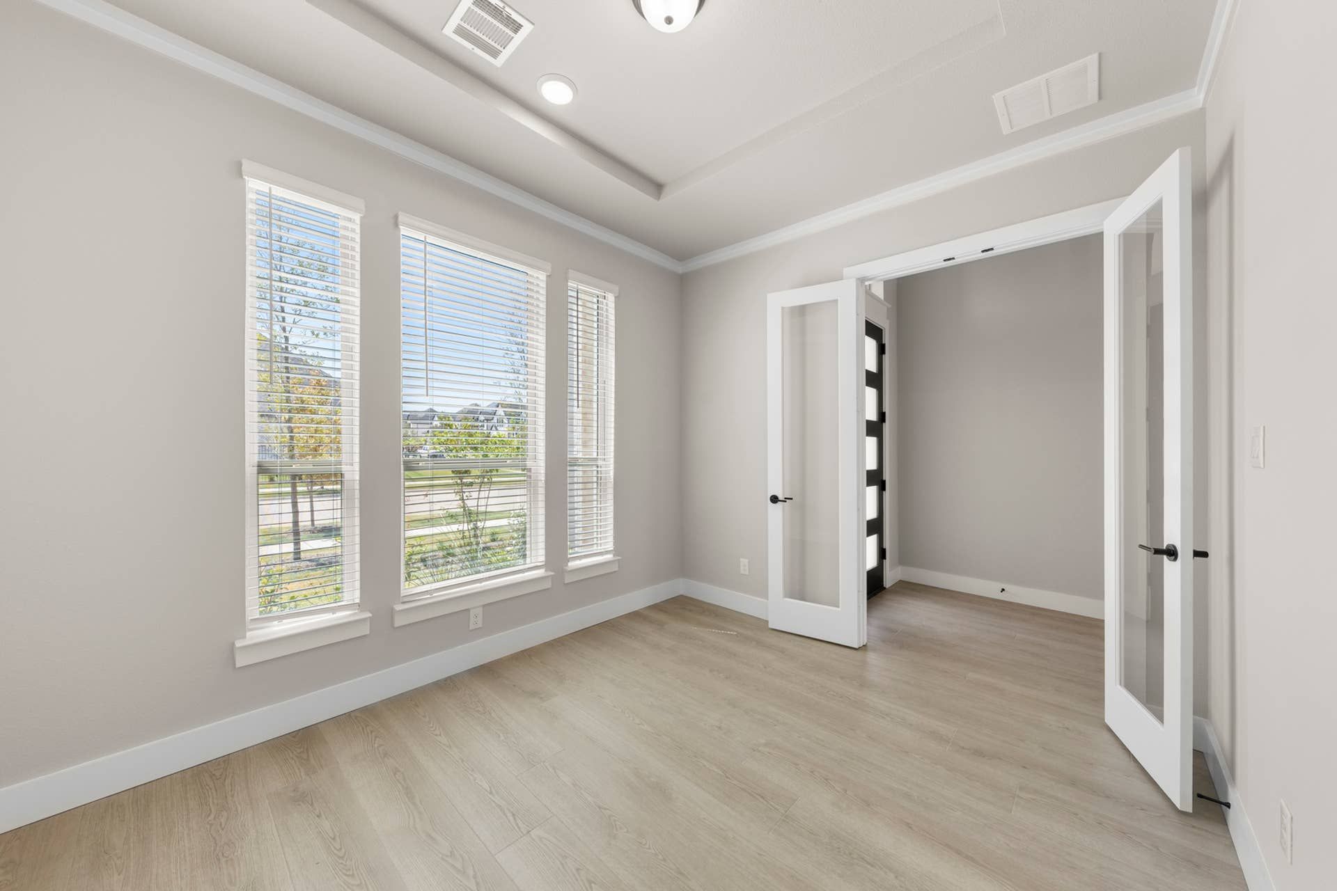 Bright study room with French doors and large windows.
