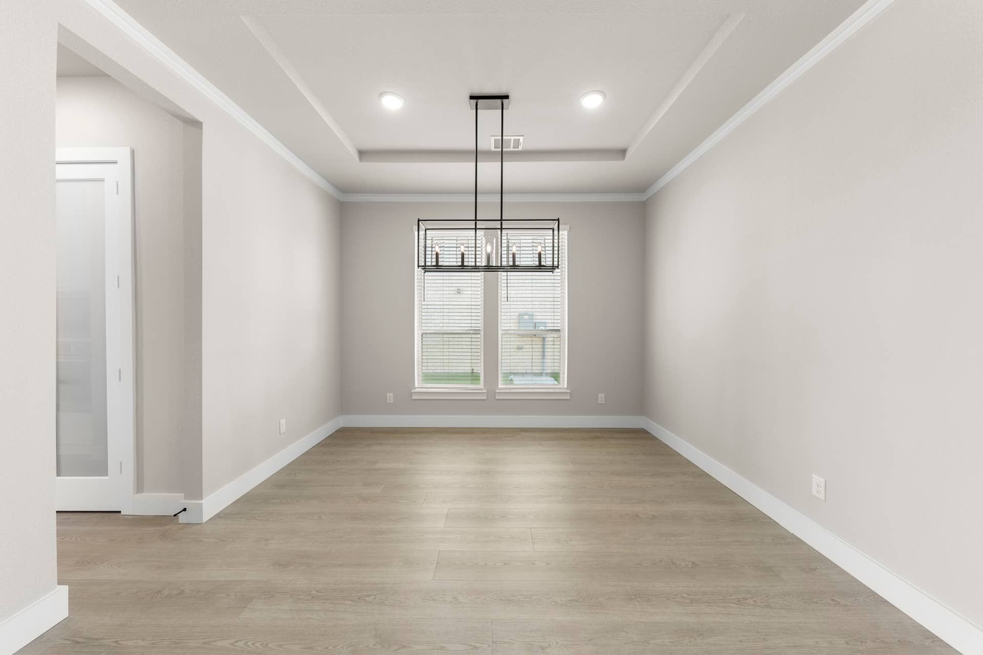 Spacious dining room with modern chandelier and hardwood flooring.