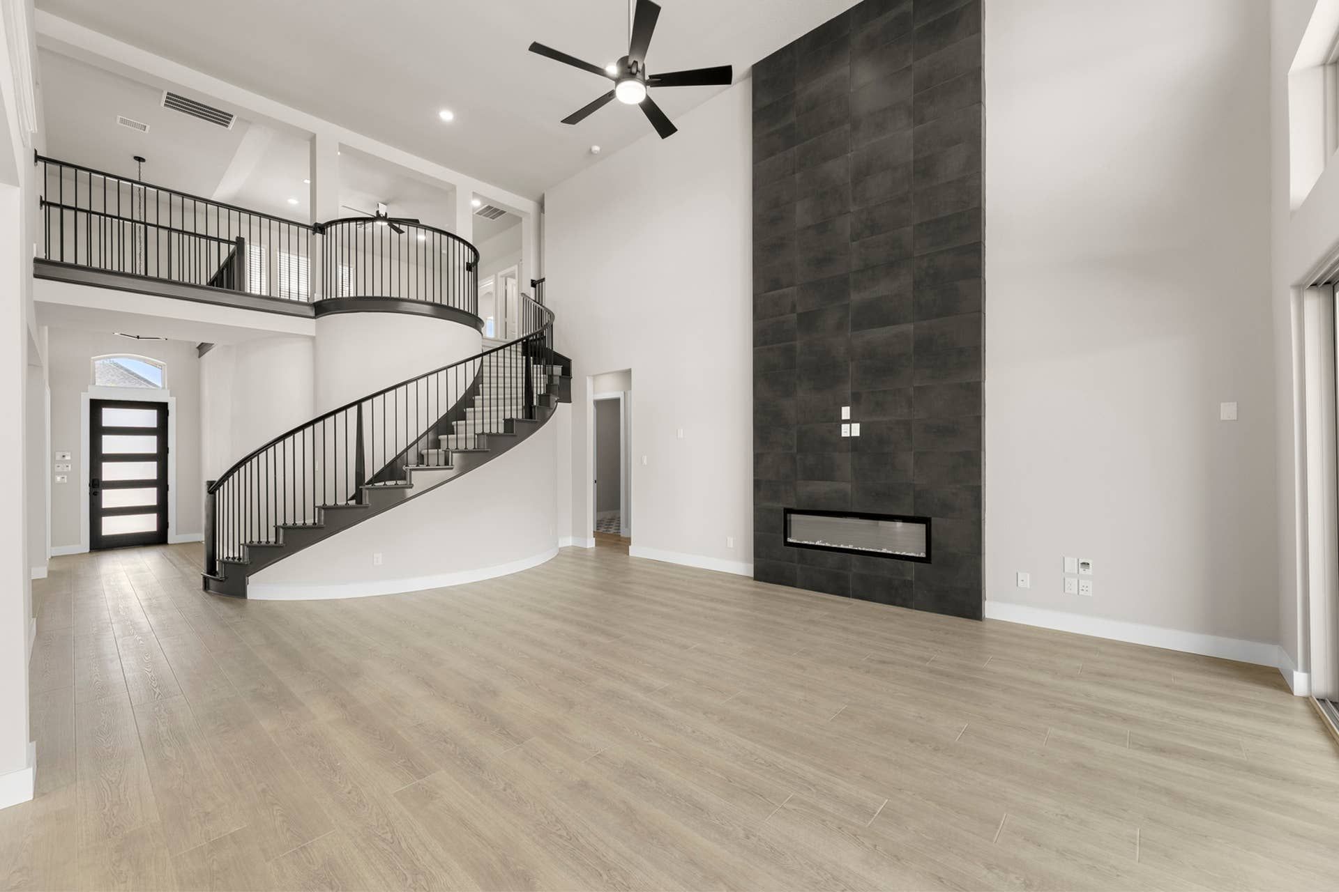 Modern interior with spiral staircase, high ceiling, and sleek fireplace.