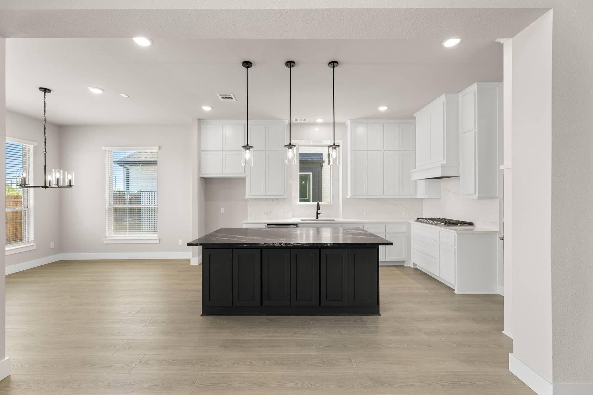 Modern kitchen with black island, white cabinetry, and pendant lighting.