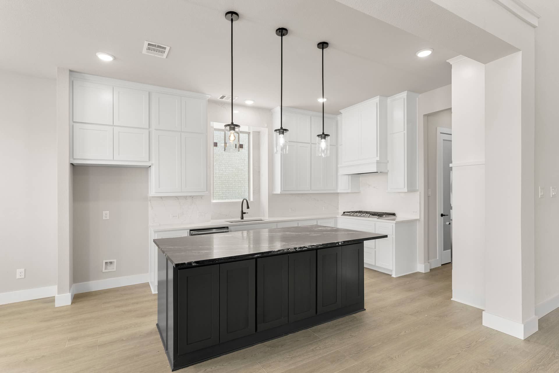 Modern kitchen with white cabinetry, black island, and pendant lighting.