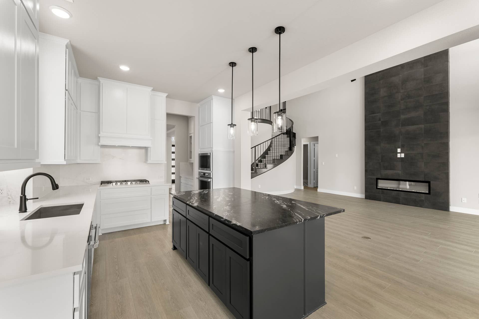 Modern kitchen with black island, white cabinetry, and spiral staircase.
