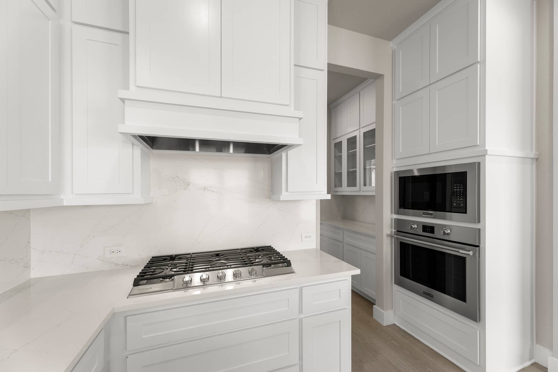 Modern kitchen with white cabinetry, stainless steel appliances, and marble countertops.