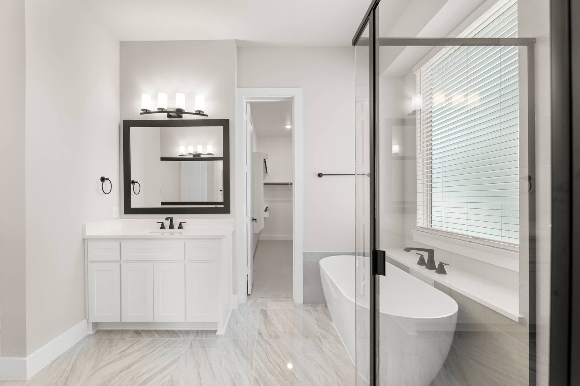 Modern bathroom with freestanding tub, glass shower, and elegant vanity lighting.