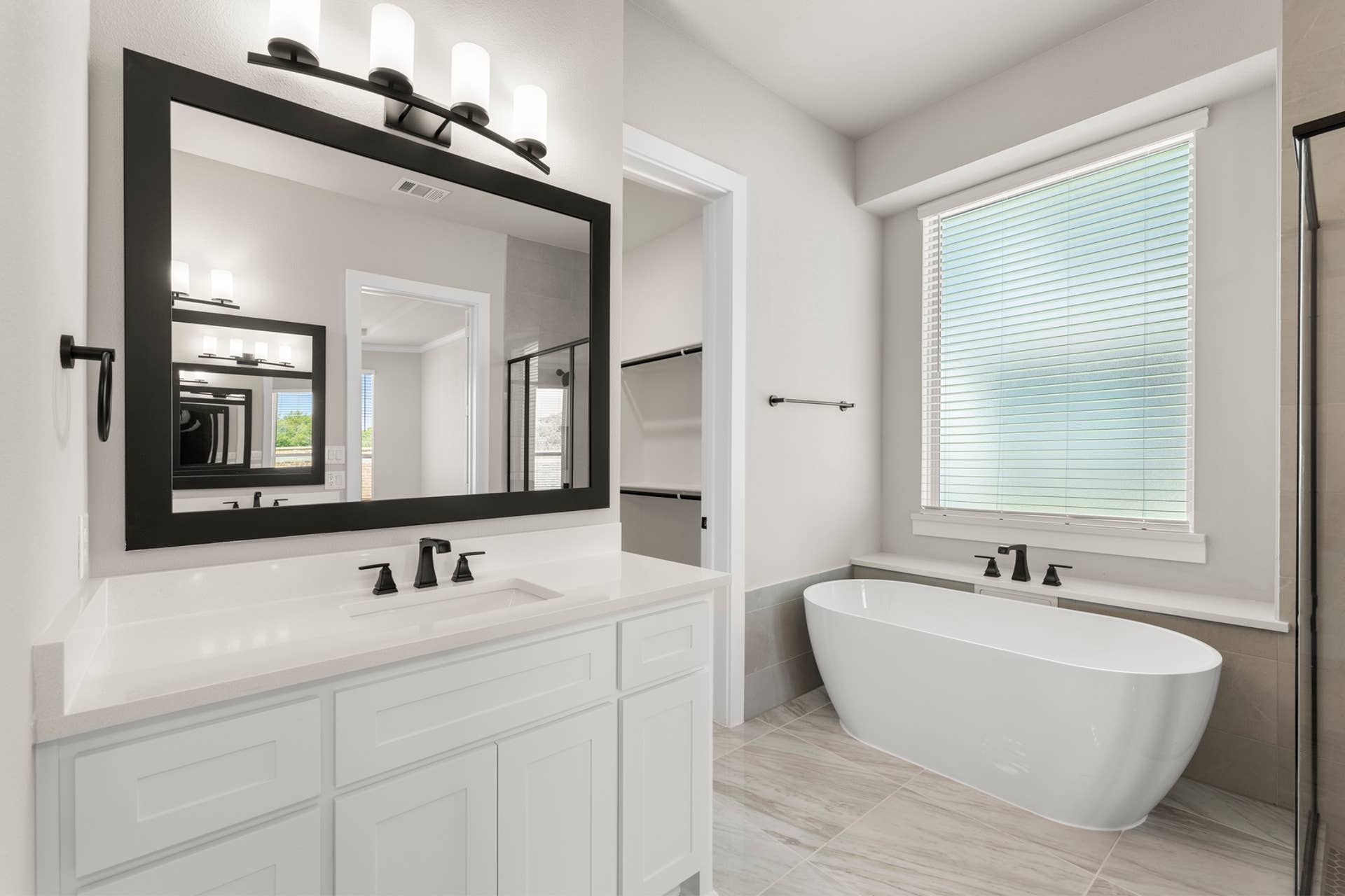 Modern bathroom with freestanding tub, large mirror, and elegant lighting fixtures.