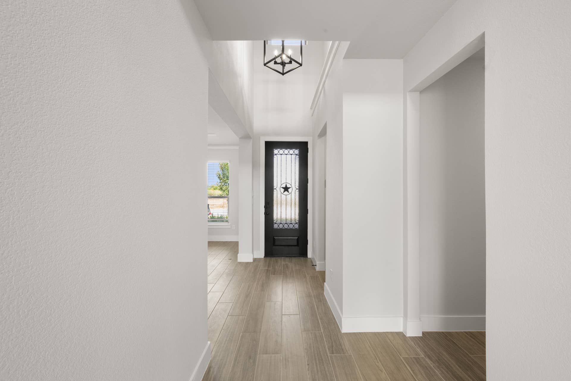 Bright entryway with wooden flooring and decorative front door.