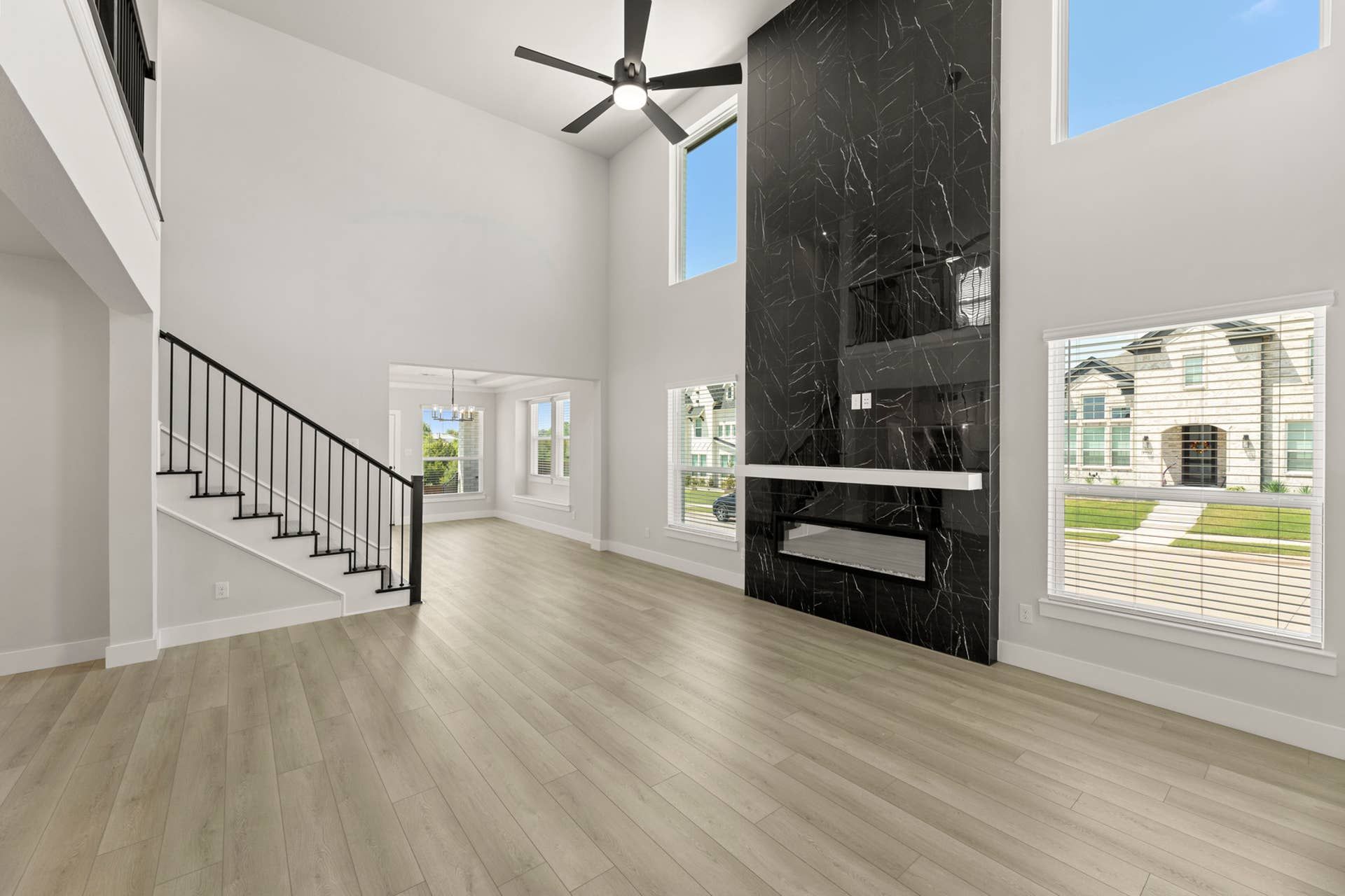 Modern living room with tall ceilings, black marble accent wall, and sleek staircase.