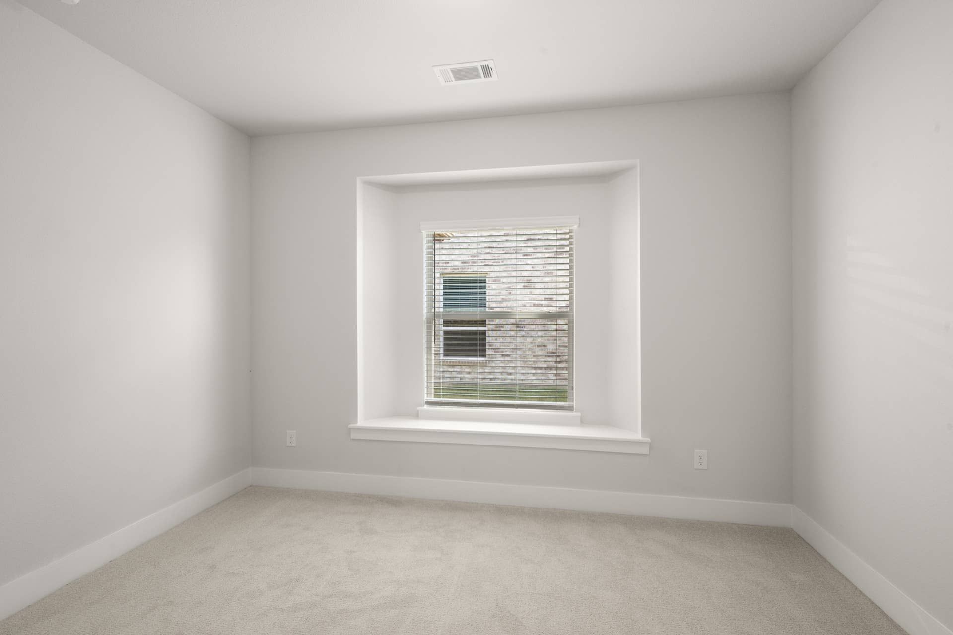 Minimalist room with carpeted floor and large recessed window.