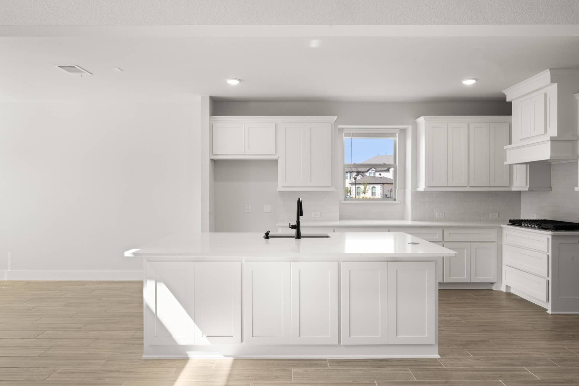 Modern kitchen with white cabinetry, island, and natural light from window.