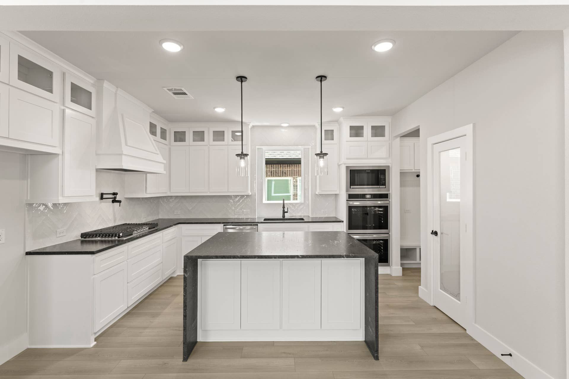Modern kitchen with white cabinetry, black countertops, and pendant lighting.