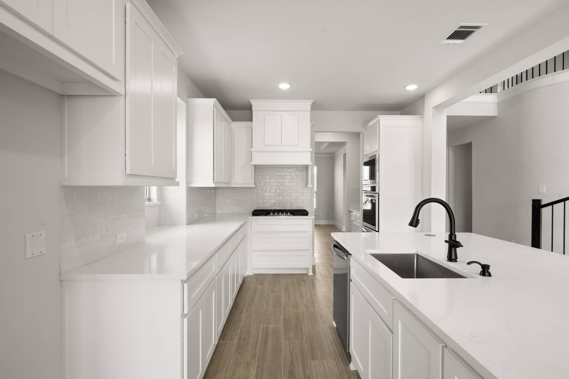 Modern kitchen with white cabinets, island sink, and wood flooring.