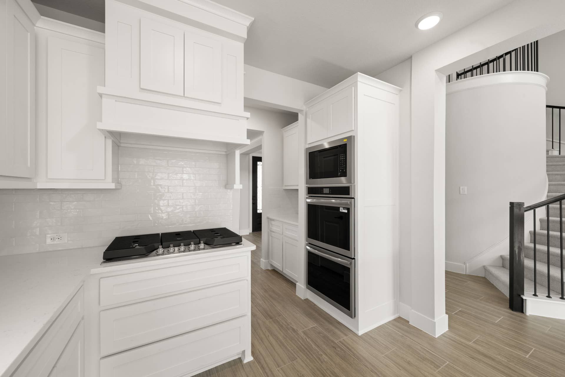Modern kitchen with white cabinetry, built-in appliances, and wood flooring.