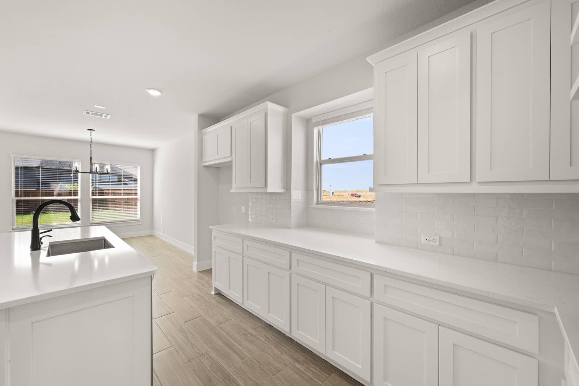 Bright kitchen with white cabinetry, large windows, and modern fixtures.